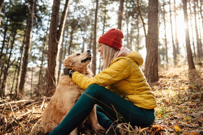 Une femme et son golden retriever ensemble au milieu de la forêt